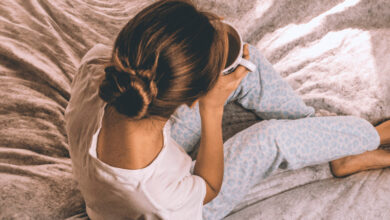 La imagen muestra una chica bebiendo una taza de leche sobre la cama